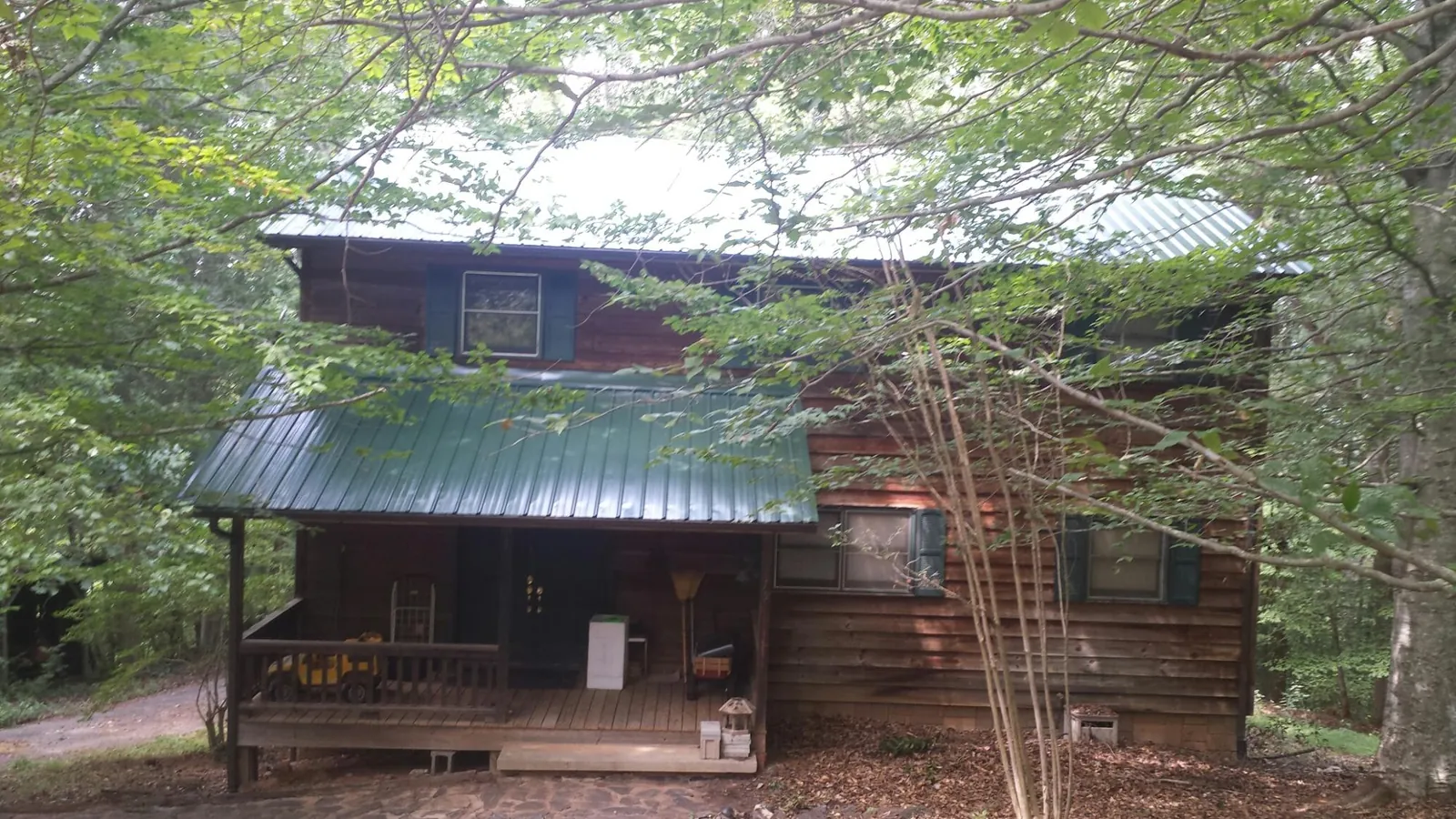 Green metal roof and covered porch on a log cabin in Buhler