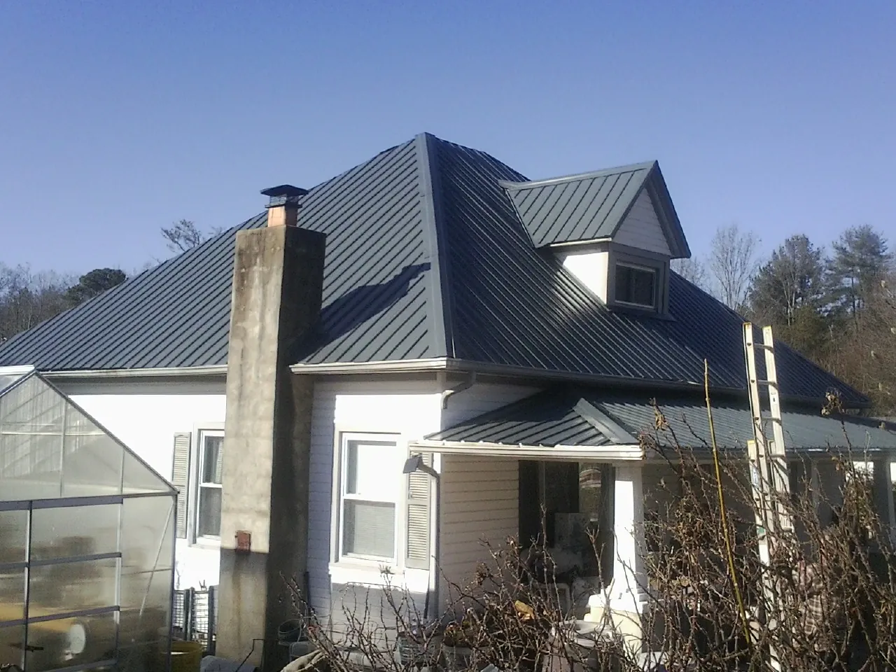 Dark blue standing seam metal roof on a white farmhouse with dormer — Slate & Tile Roof Repair by Roofing Brothers in Buhler