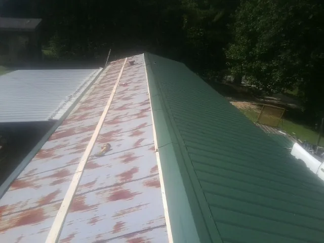 Old rusted panels beside newly installed green metal roofing — Wind Damage Roof Repair by Roofing Brothers in Buhler