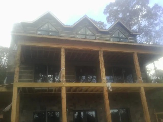 Dormers and porch framing on a large log home under construction — Roof Coating work by our crew in Buhler