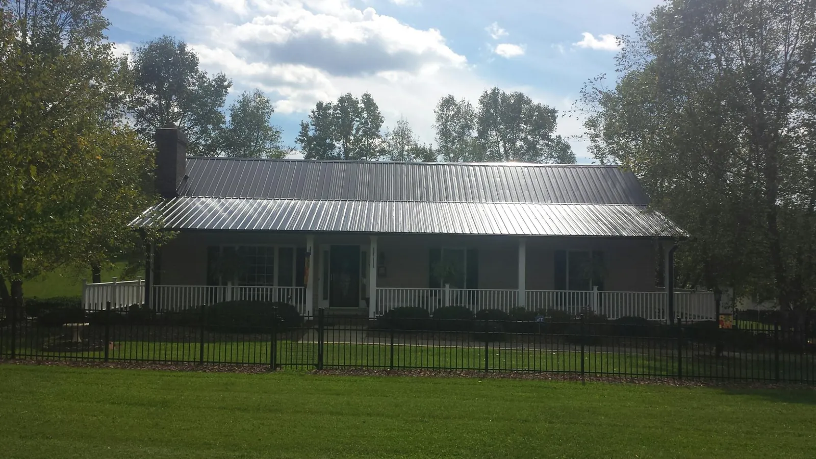 Gray metal roof on a brick ranch with a full width front porch — Gutter Guard Installation work by our crew in Buhler