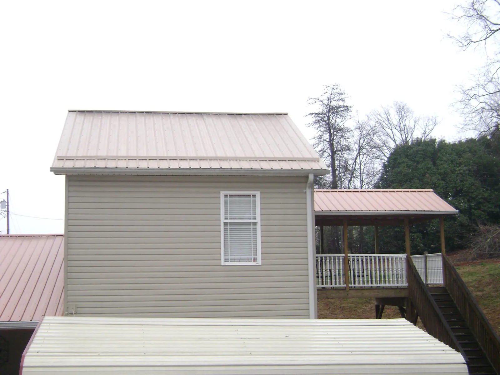 Tan metal roofs on a two story addition and attached porch, from a Roof Replacement job in Buhler