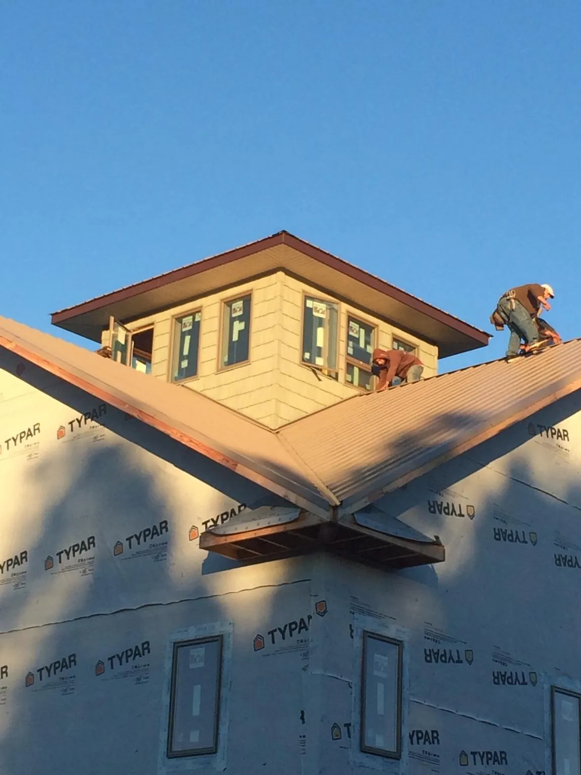 Roofers working around a rooftop cupola on a new metal roof at sunset — Roof Waterproofing in Buhler by Roofing Brothers
